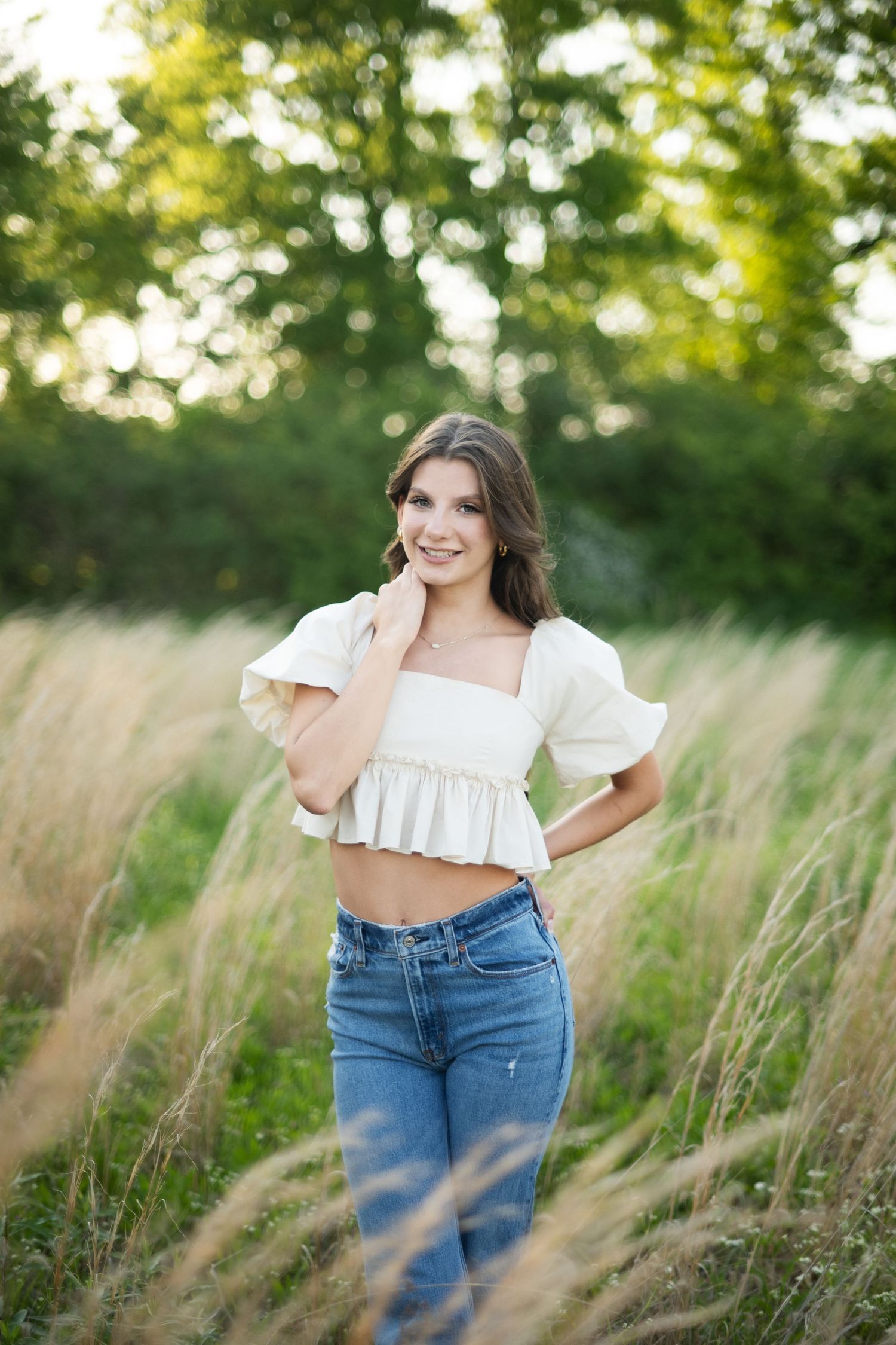 Person in purple dress sits in sunlit meadow during golden hour with joyful expression.