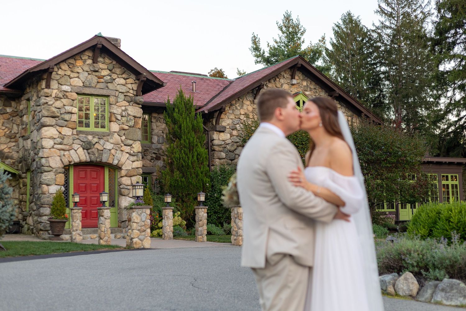 A romantic wedding photo series at a rustic stone venue with red doors and natural greenery surroundings.