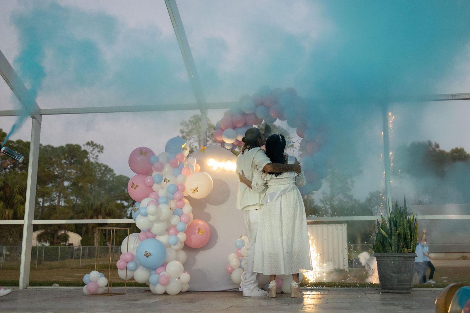 Emotional gender reveal moment with blue smoke and balloons