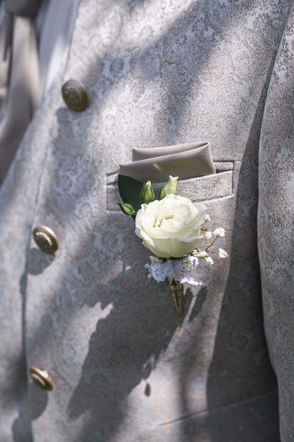 Blumenboutonniere des Bräutigams im Anzug mit Zwölfknopf-Silhouette und Jaquardmuster von Wilvorst.