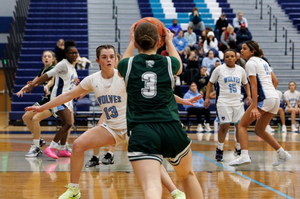 Basketball players in action with one attempting to block opponent in green jersey.
