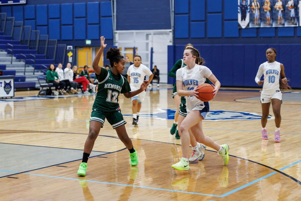 Basketball players in white and green uniforms compete during a game on a blue court.