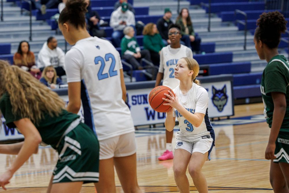 Athletes in white and green jerseys position themselves during a basketball game.
