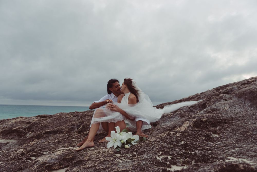 A bride and groom pose together on a cliff in Tulum, Mexico.