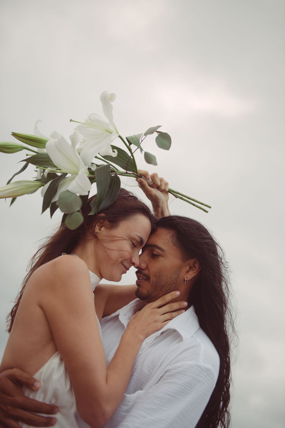 A bride is holding a bouquet of flowers while the groom is embracing her.