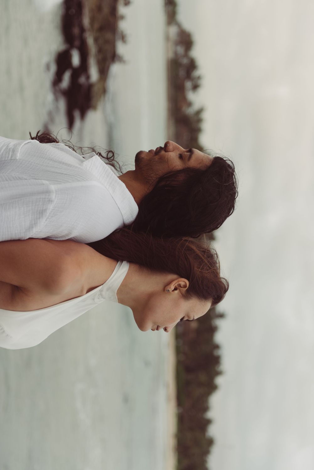An artistic portrait of a bride and groom posing back to back on the beach in Tulum, Mexico.