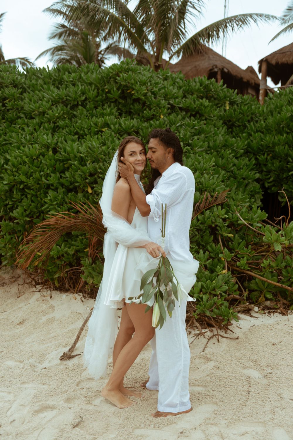 Romantic elopement featuring the couple smiling and posing on the beach in Tulum, Mexico.