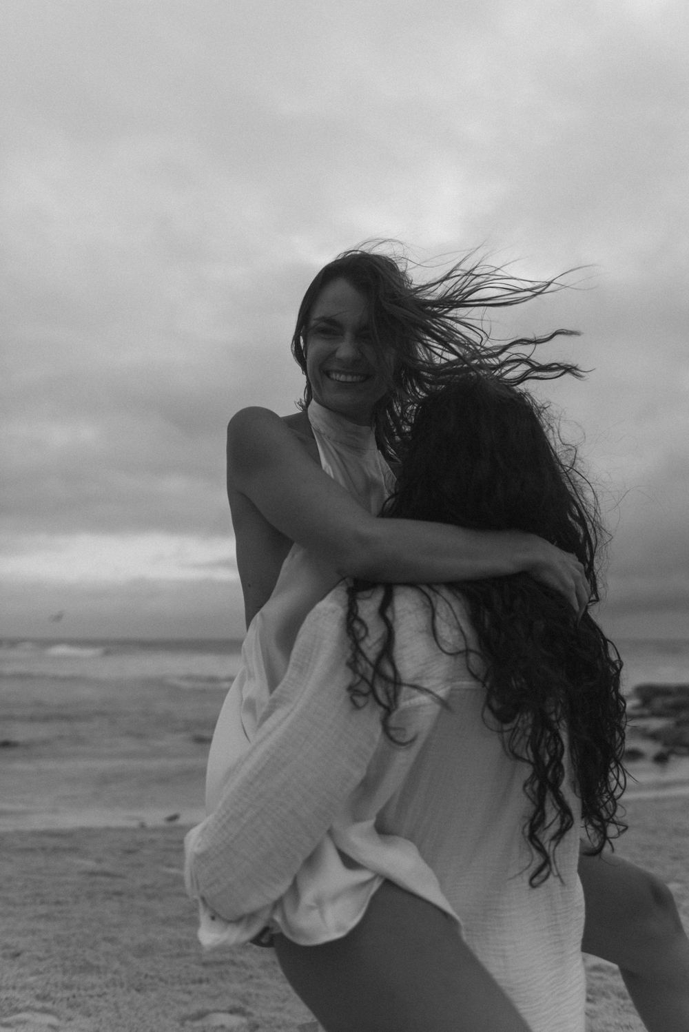 Black and white photo of a couple smiling and embracing on the beach.