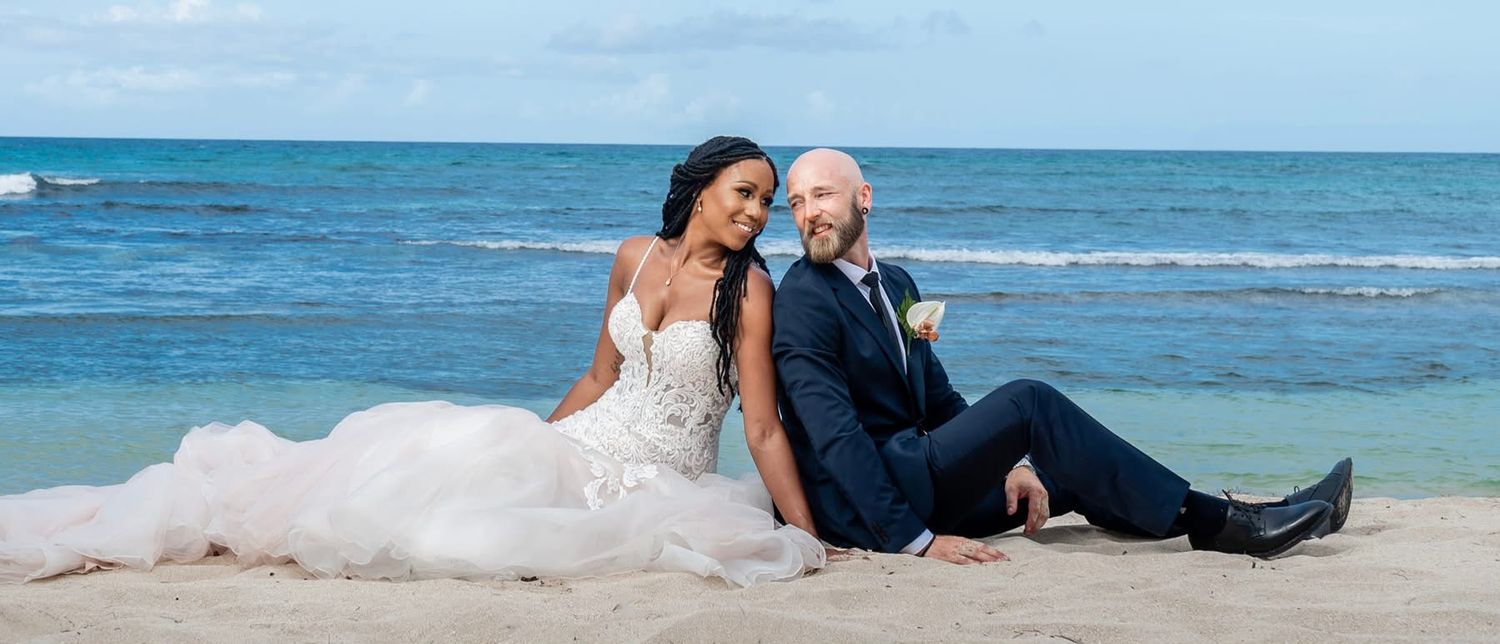 Newlyweds share intimate moments along a tropical beach setting.