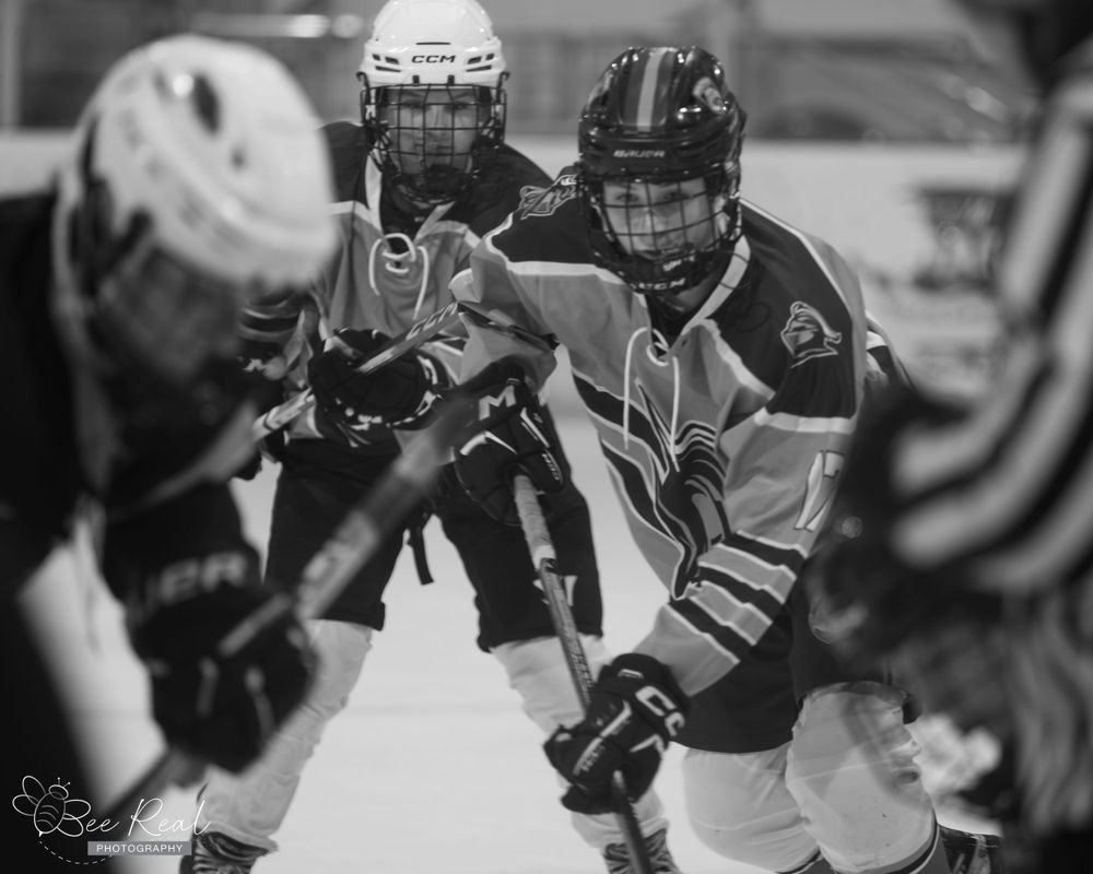 Black and white photo of hockey players battling for position during game.