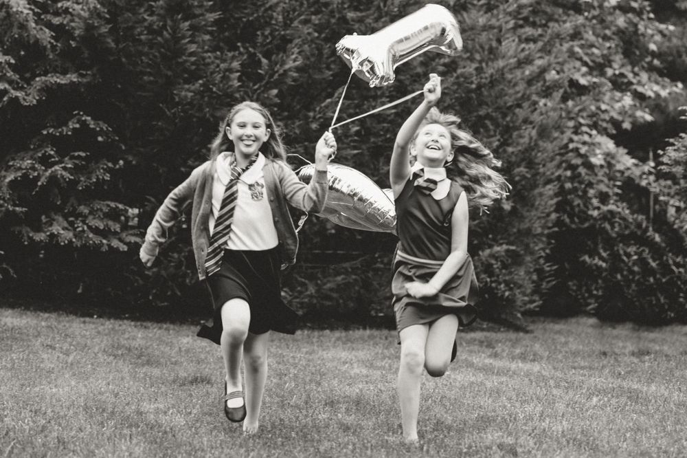 Two children run joyfully through a field carrying flags in this vintage black and white photograph.