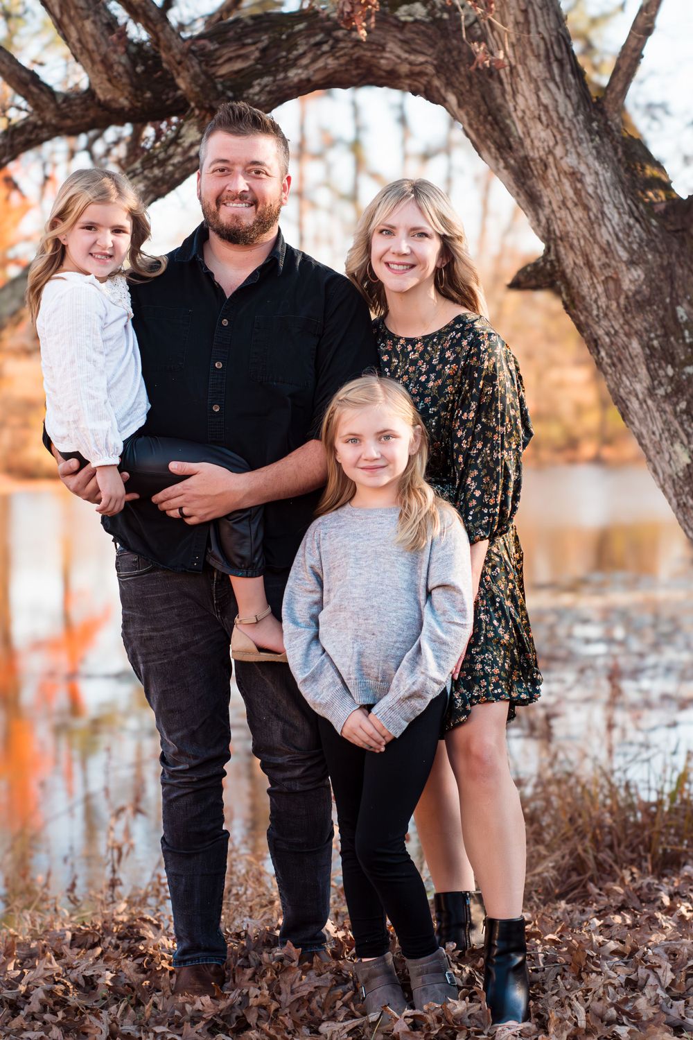 Family portrait taken under large tree branch during autumn season.