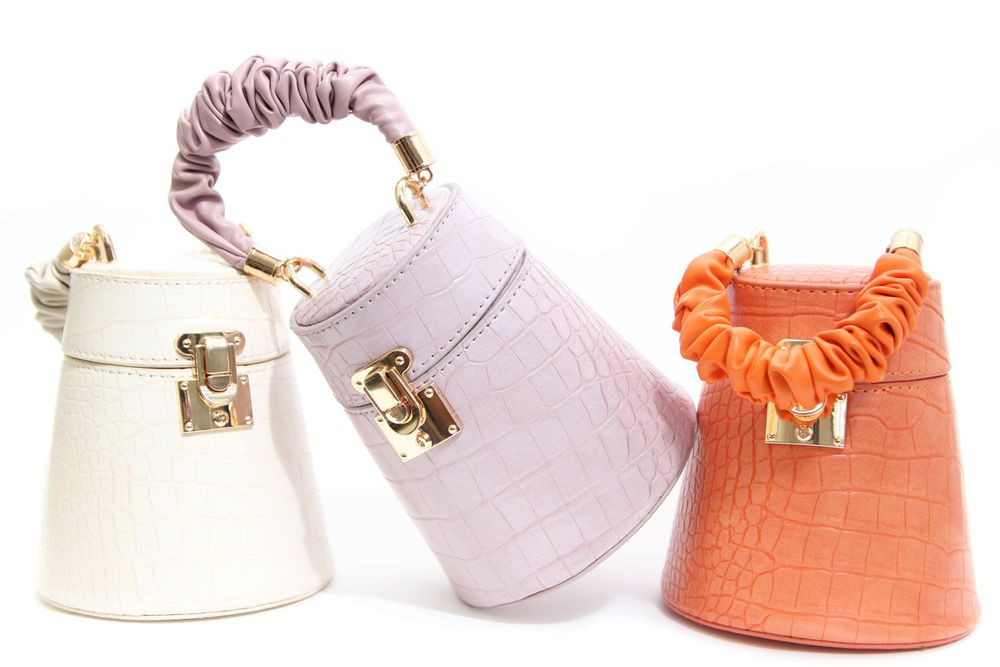 Three small purses with scrunchie handles in white, lilac, and orange colors arranged in a row with gold metal clasps.