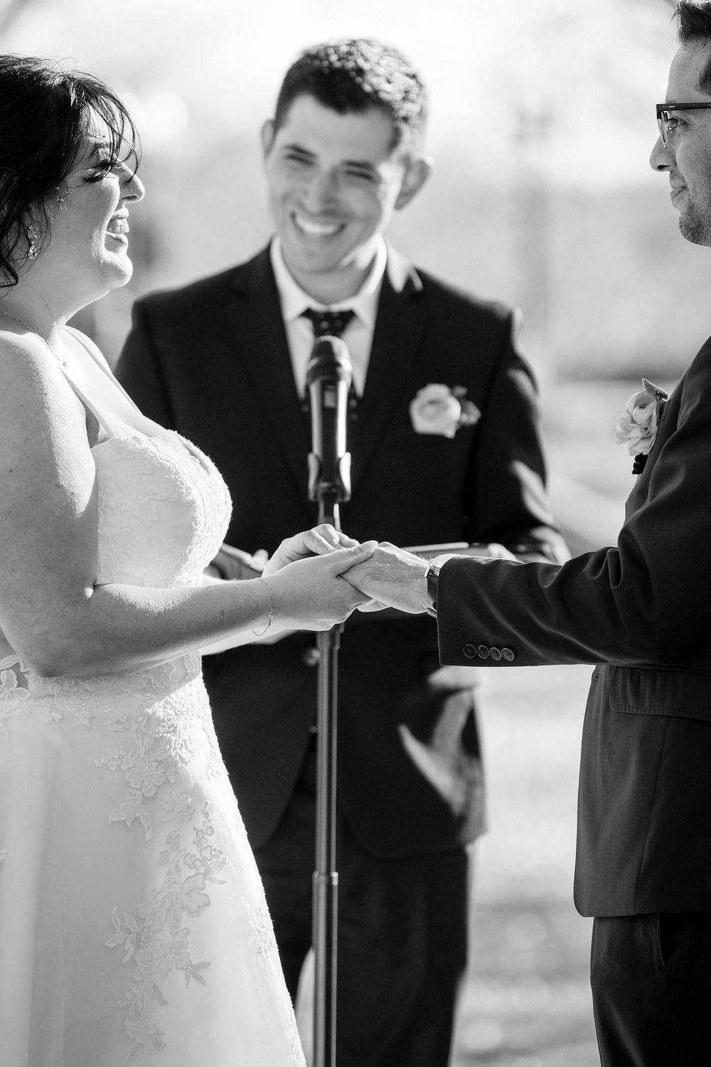 Black and white wedding ceremony photo showing a couple exchanging vows at the altar with an officiant present.