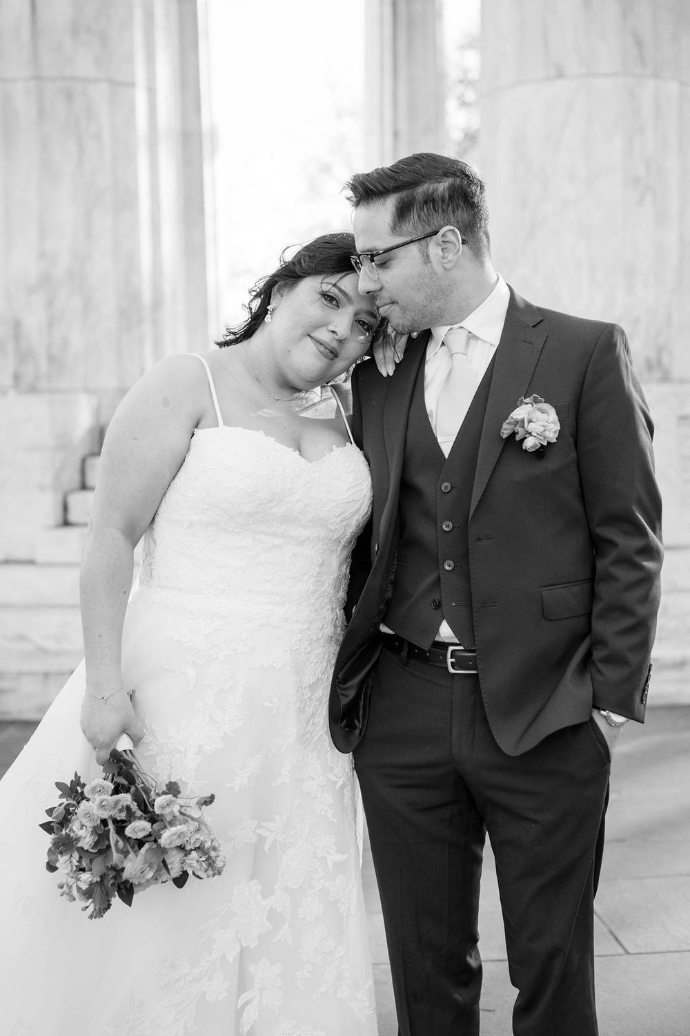 A romantic wedding couple embraces in a series of black and white portraits against a light architectural backdrop.