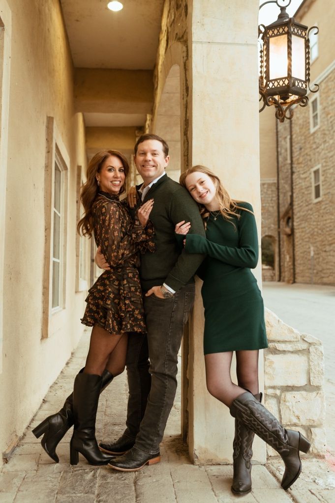 A couple in coordinated outfits poses playfully in a series of photos along a stone archway corridor.