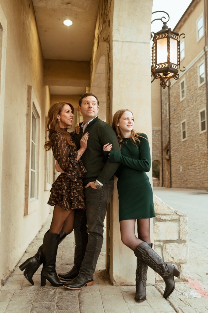 People pose playfully in a stone colonnade hallway with arched architecture and lantern lighting.