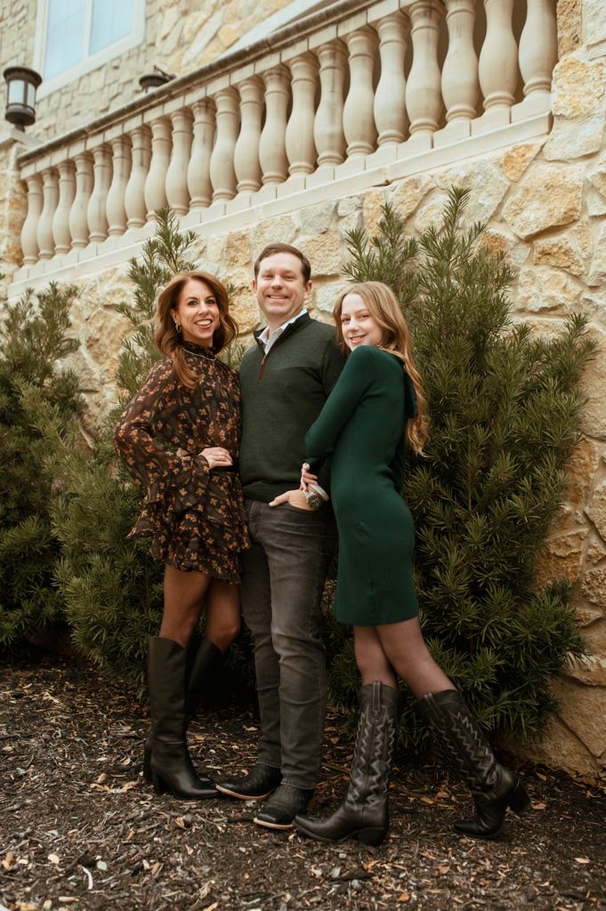 Playful family portrait session against stone wall with decorative balusters.