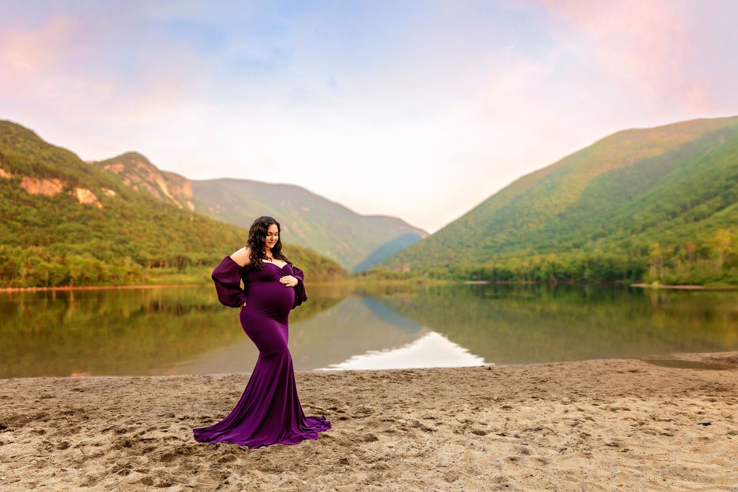 Lakes Region NH maternity photography of a pregnant woman in a purple gown, scenic mountain lake portrait celebrating motherhood.