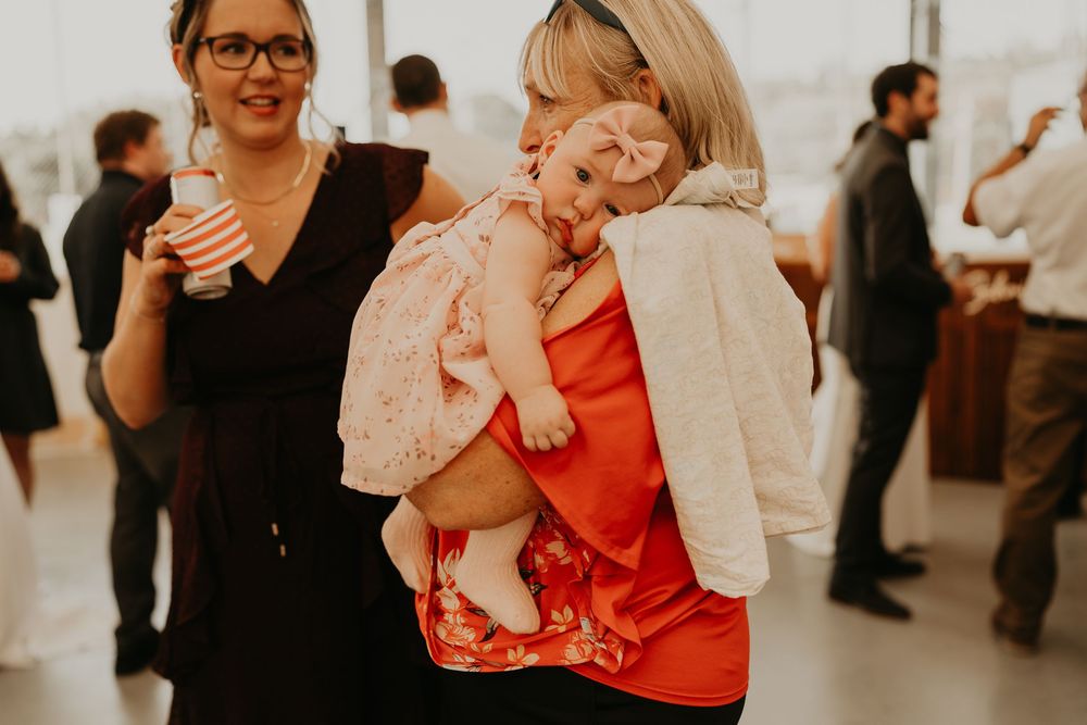 baby with head on should on wedding guest as they mingle