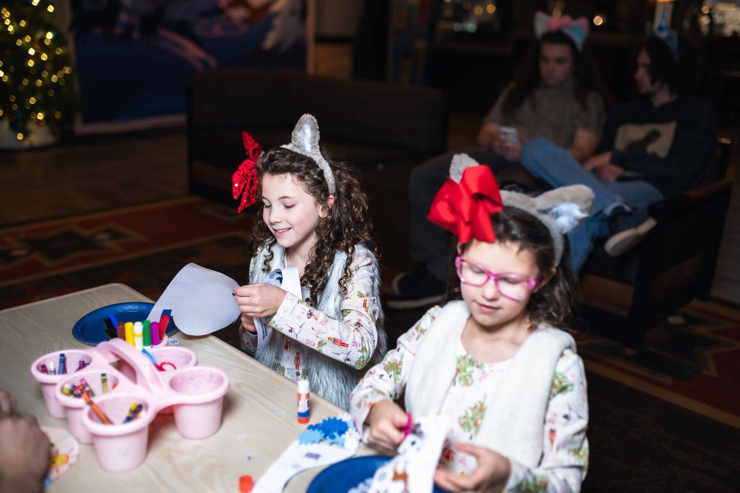 Children gather around tables at a craft workshop, making holiday decorations and art projects.