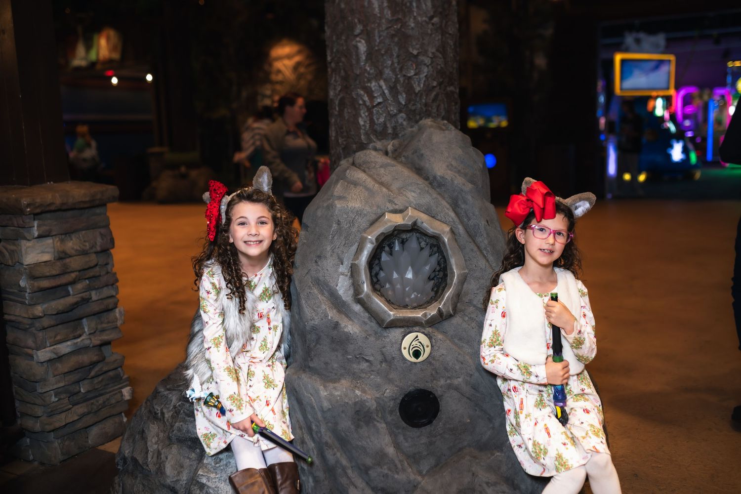 People pose playfully in front of a dark stone wall with decorative lighting in an indoor entertainment venue, playing Magic Quest.