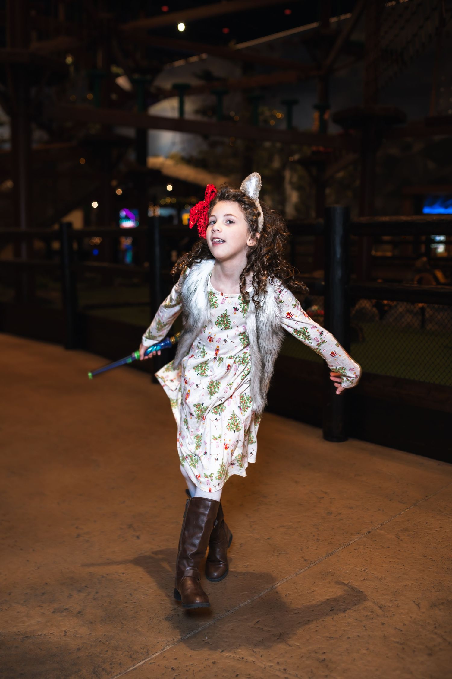 A person in a floral dress and boots performs a playful dance sequence in a dimly lit outdoor setting.