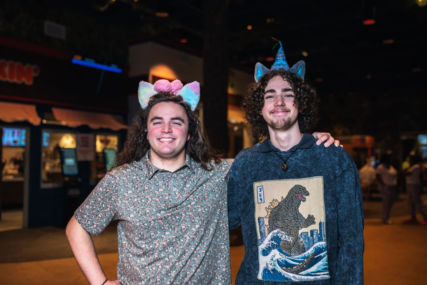Friends gather together wearing casual attire and smiling at an indoor venue with dim lighting.