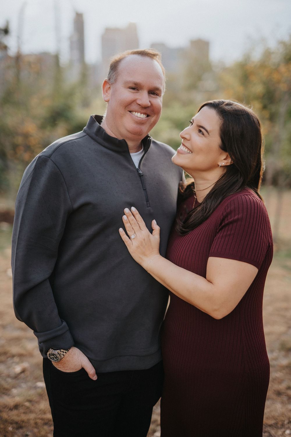 A couple shares joyful moments and laughter while posing together outdoors during a photo session.