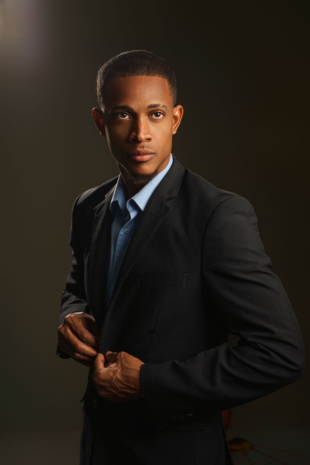 Professional portrait series showing a person in a dark business suit against a shadowy background with dramatic lighting.