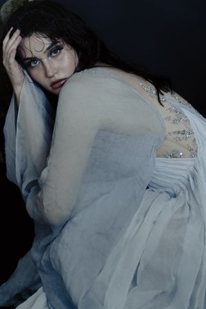A series of moody artistic portraits featuring someone in a delicate white vintage-style dress against a dark background.