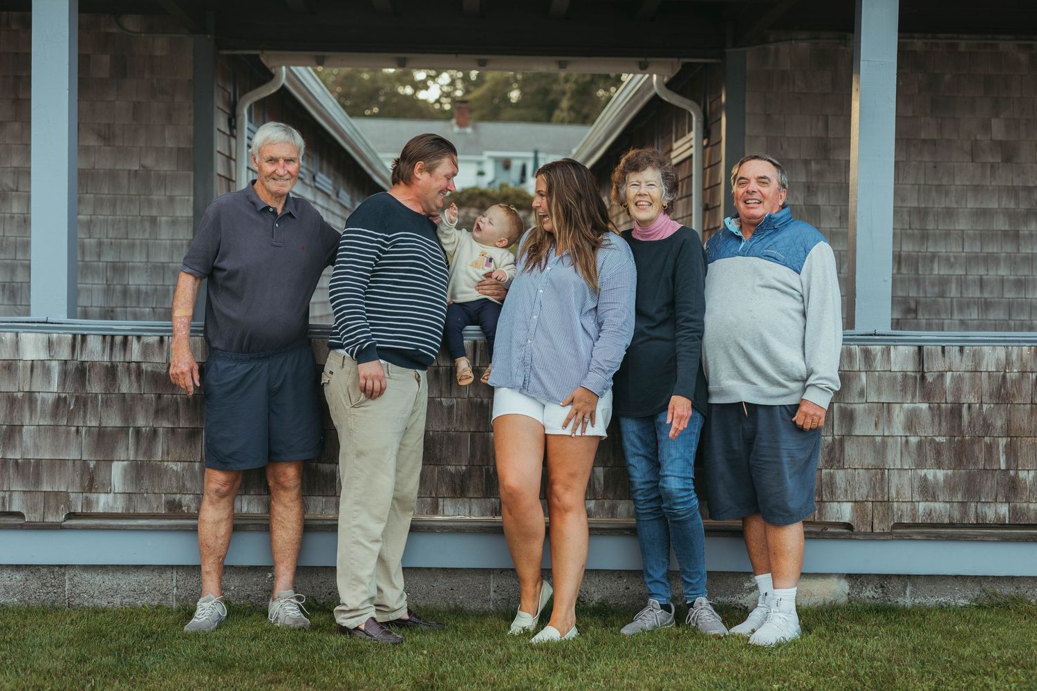 Large group photo of people gathered outside a rustic building.