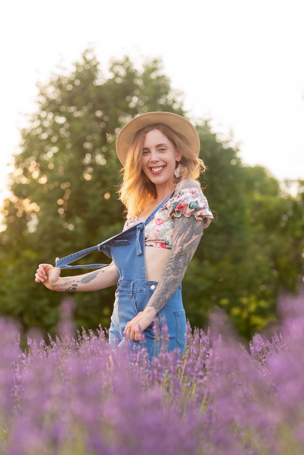 A person in overalls and a sun hat twirls joyfully in a blooming purple lavender field at sunset at R and B Lavender.