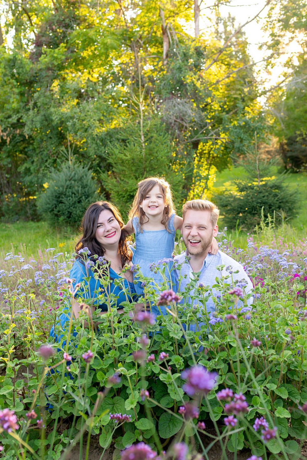 Family laughing together in a summer garden filled with purple and blue wildflowers  at the Flower Lady and Gent