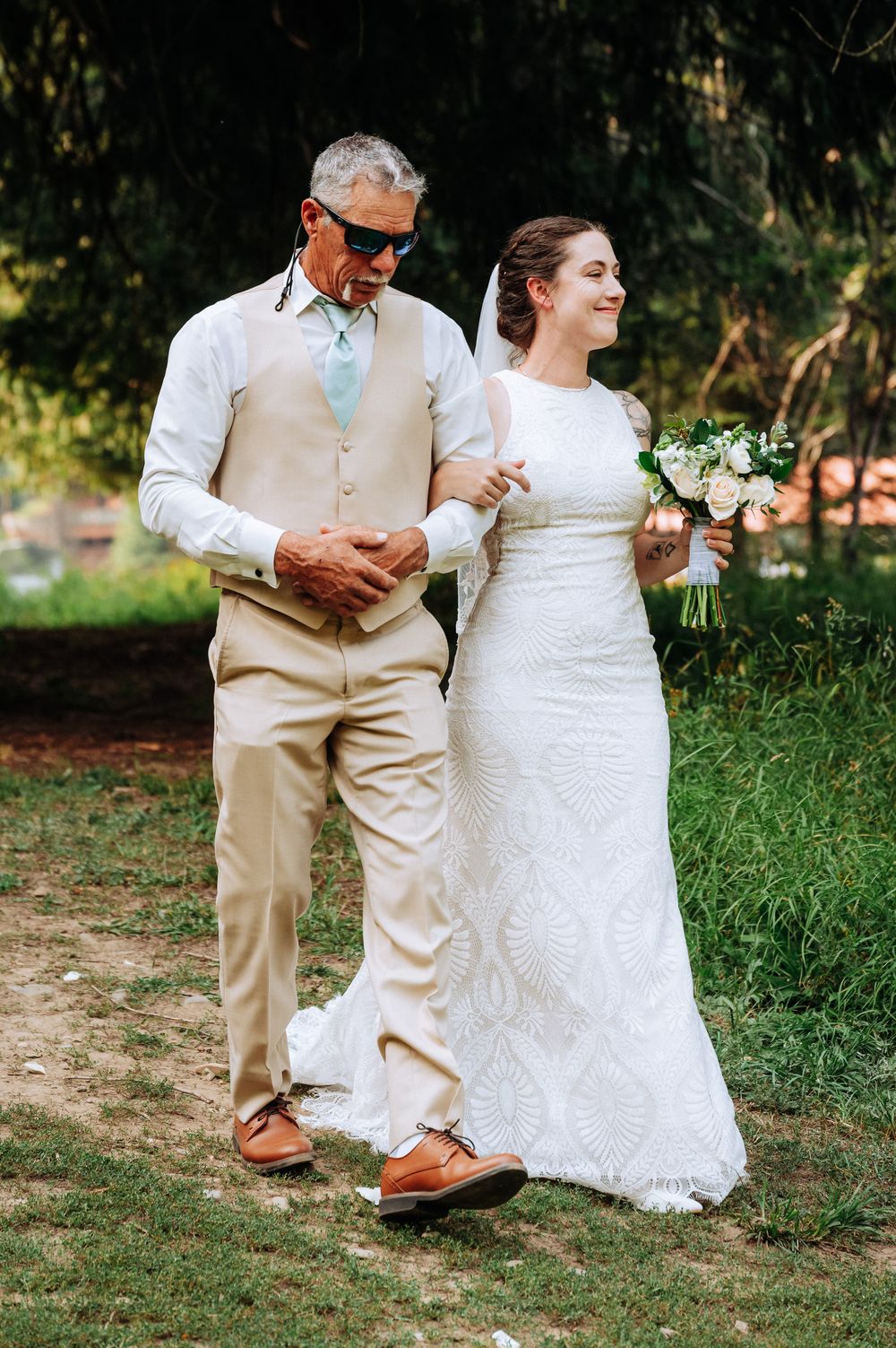 Close-up sequence of bride and groom's feet walking together on grass, showing tan shoes and white lace dress details.