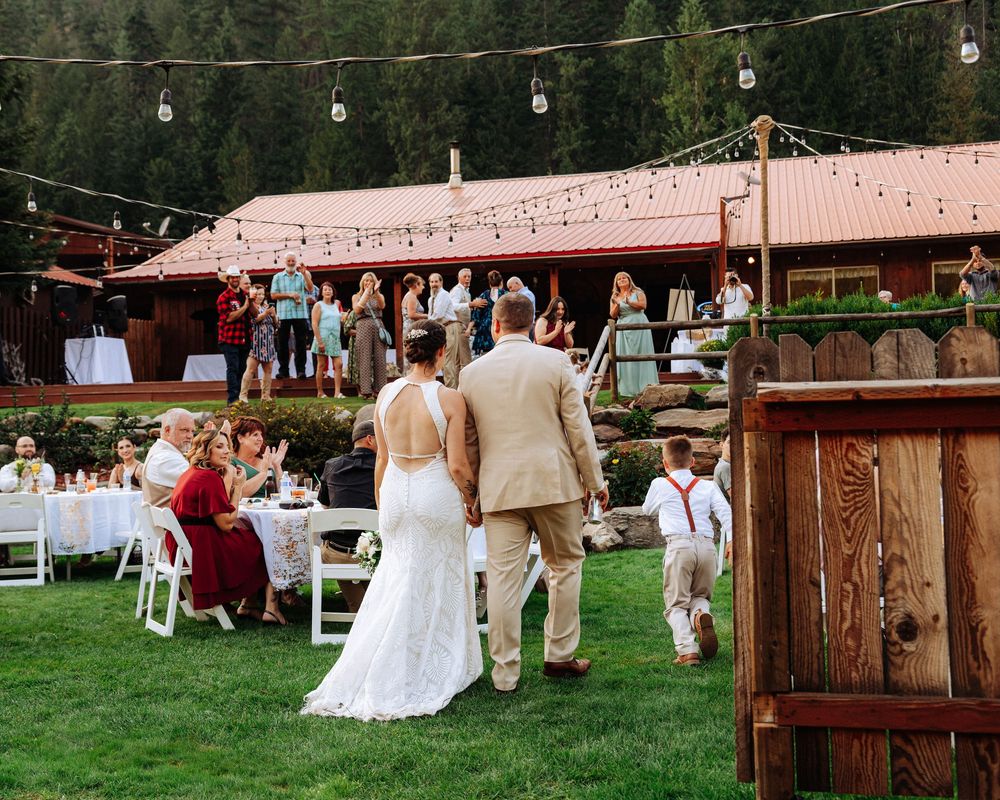 Outdoor wedding reception setup with rustic wooden decor and string lights at a countryside venue.
