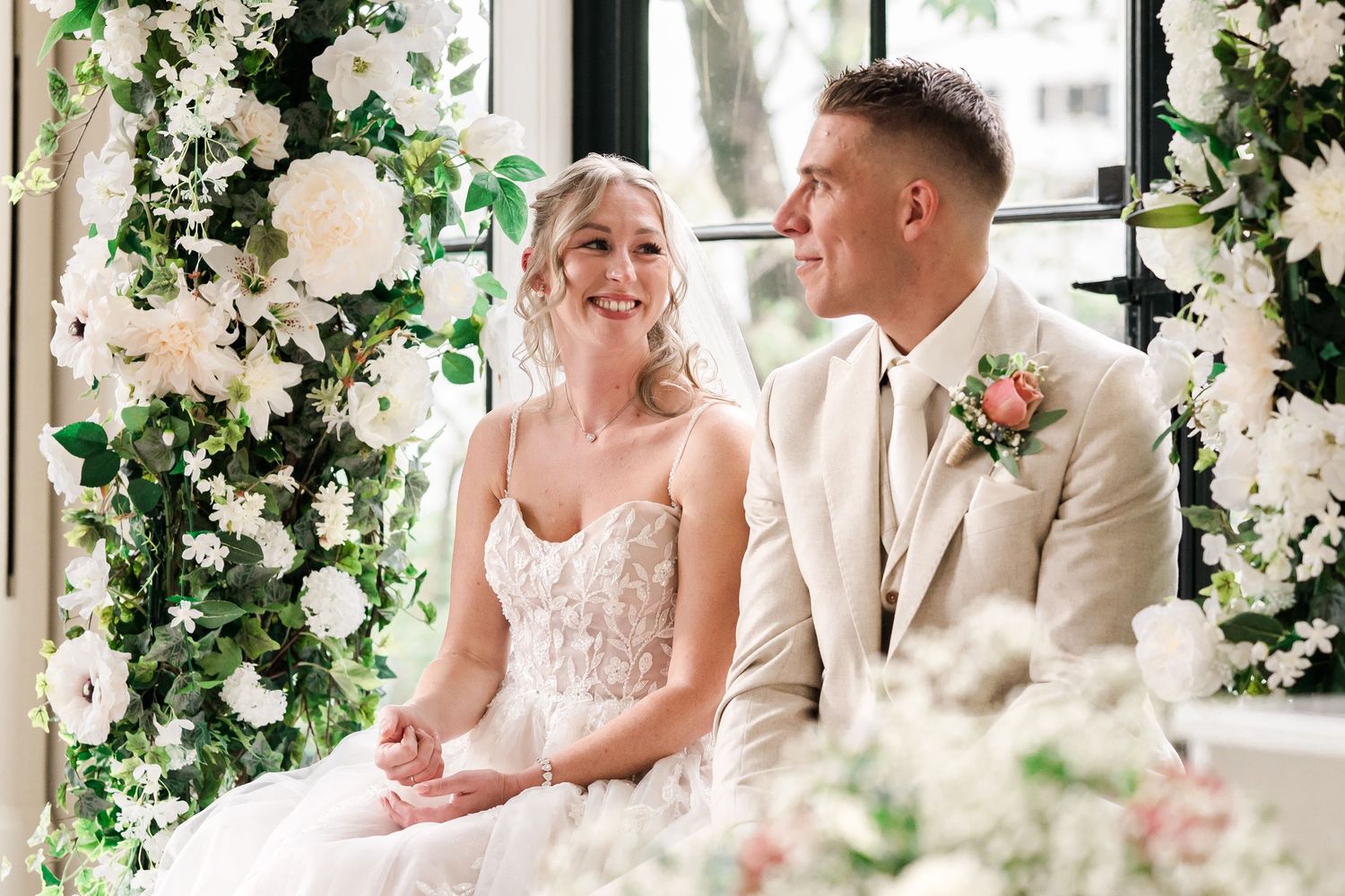 Bruid kijkt liefdevol naar bruidegom tijdens ceremonie in Oranjerie Sandenburg