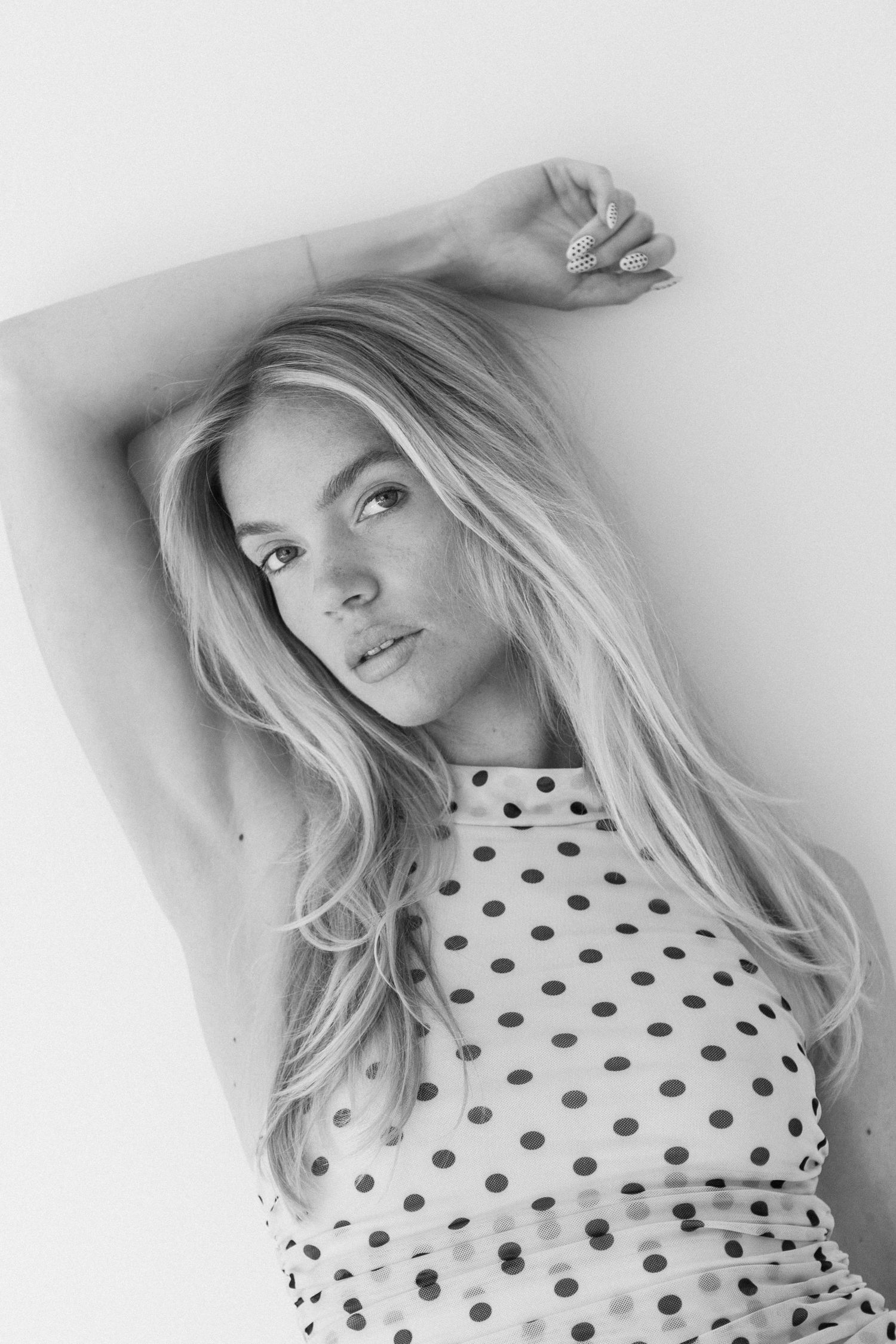 A series of black and white fashion portraits featuring a model in a polka dot top with blonde hair against a light background.