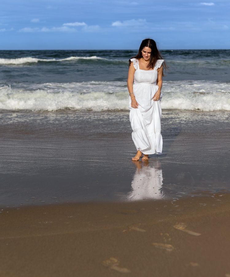 Woman in a maxi dress dress walk on the shore line in Virginia Beach, Virginia