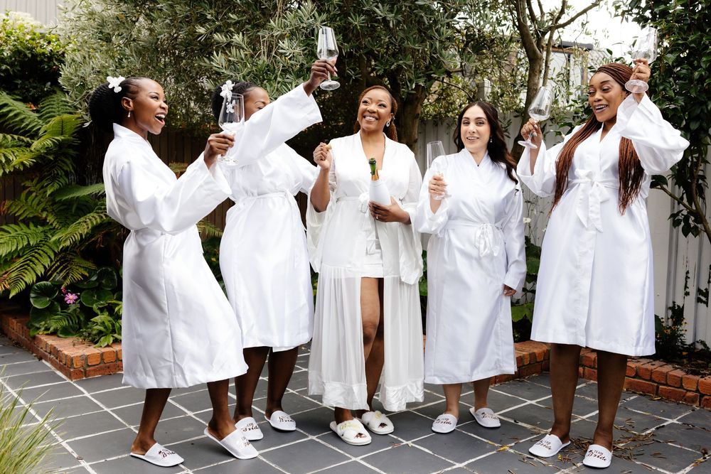 A group wearing white robes and spa attire poses together outdoors for a celebratory photoshoot.