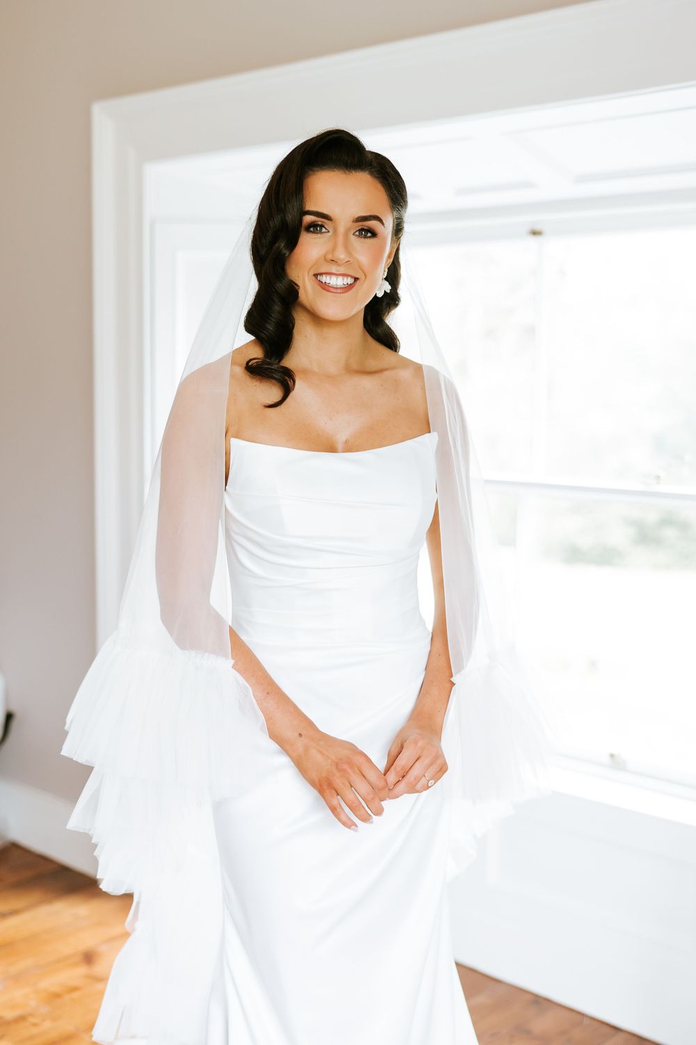 Close-up bridal portraits showing an elegant white wedding dress with ruched bodice details in a bright sunlit room.