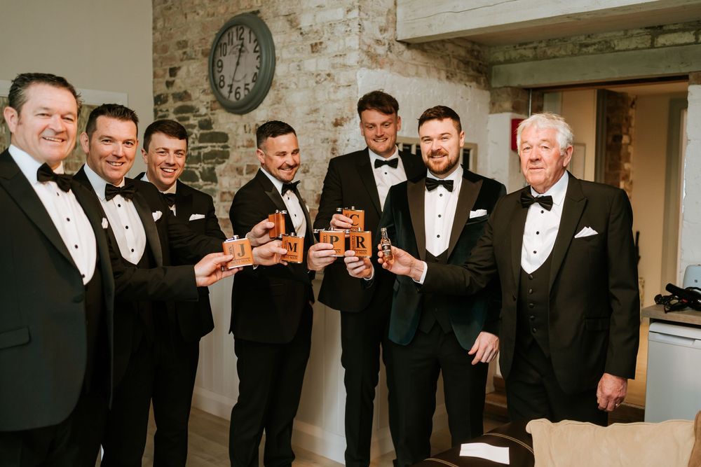 Groomsmen in black tuxedos gather together and share laughs during a wedding celebration. Bellingham Castle Conlon Photo & Film