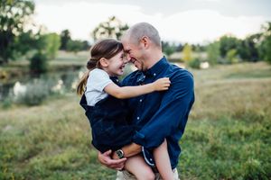 A romantic outdoor photoshoot in a grassy field at sunset shows tender embraces between a couple.
