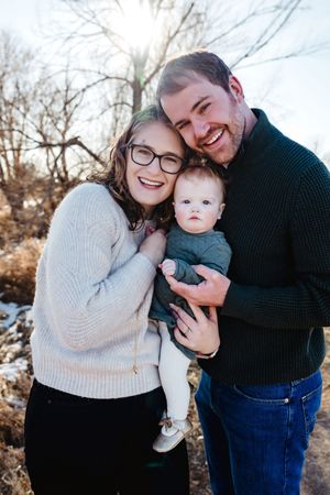 Family of three sharing tender moments outdoors in winter clothing.