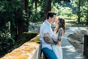 A romantic photoshoot in a wooded park setting captures intimate moments between a couple.
