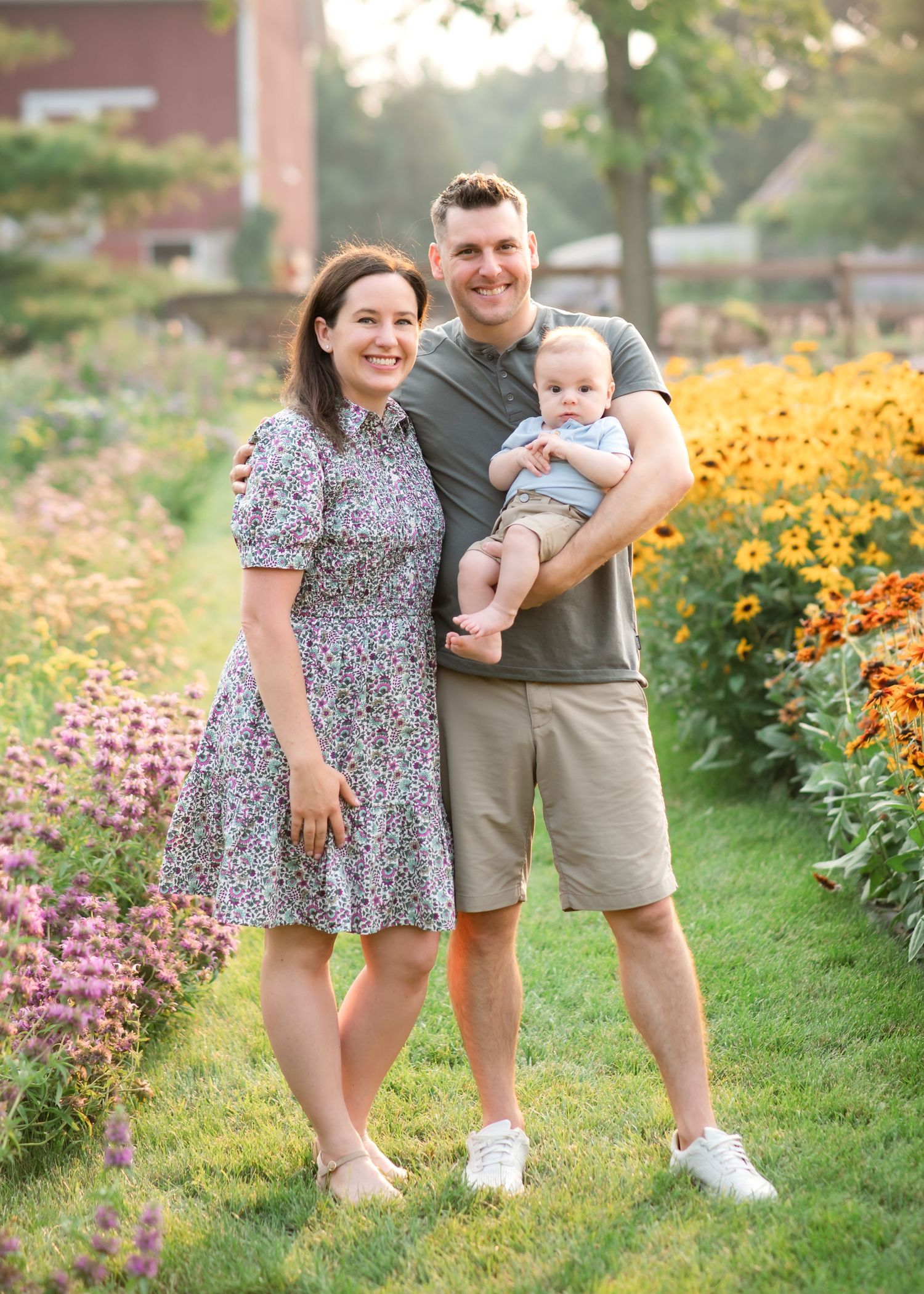Family enjoying a casual outdoor photo session near a rustic truck with purple wildflowers in the background.