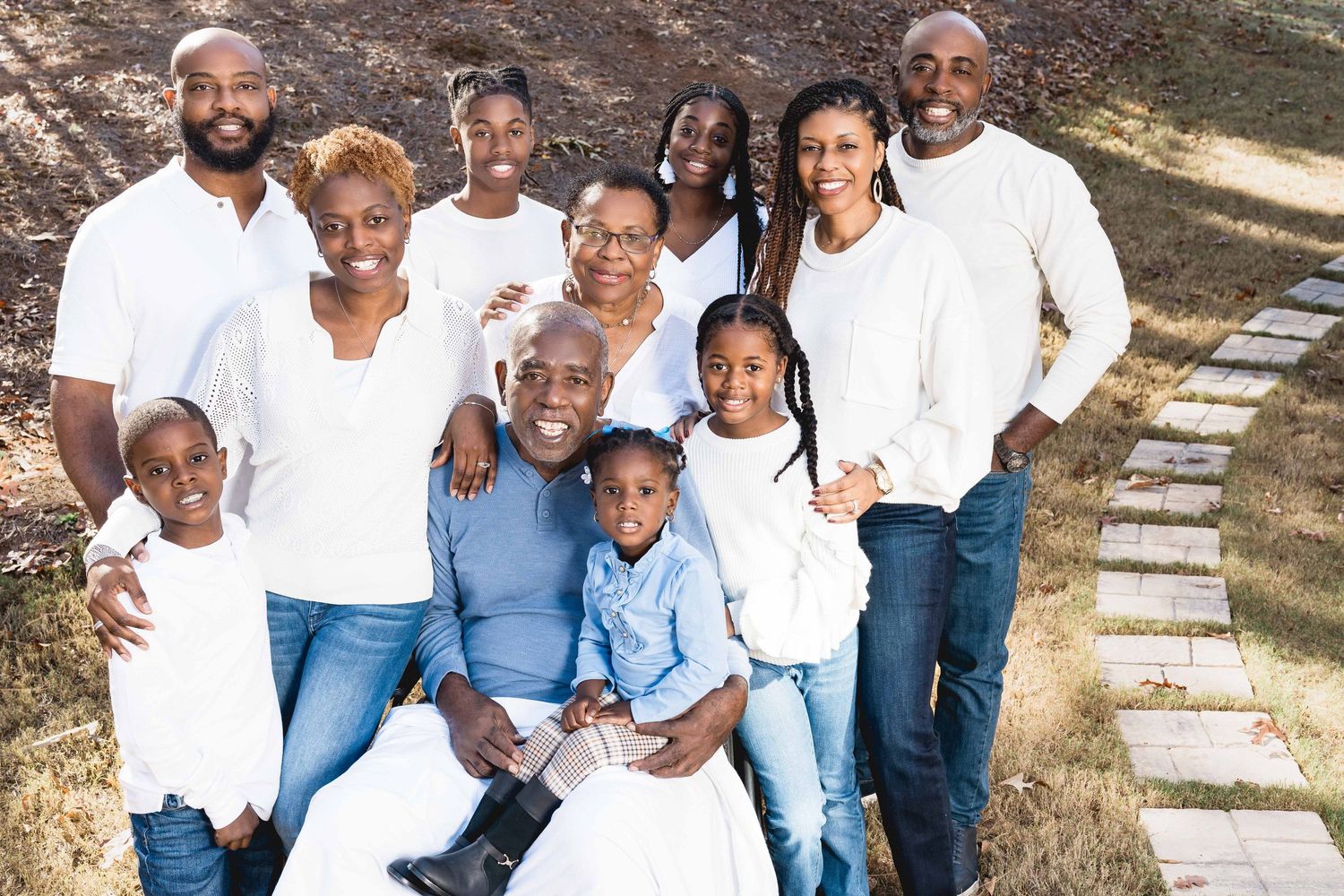 Extended family posing outdoors in coordinated blue and white outfits.