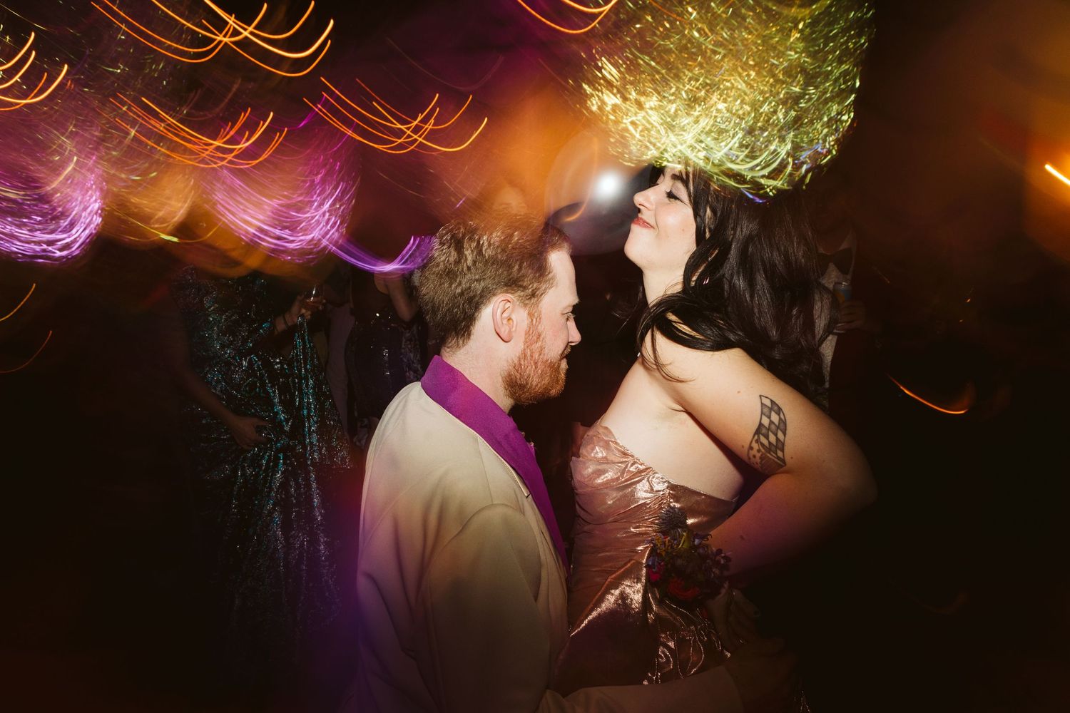A couple dances together at an indoor event venue with modern decor and lighting visible in the background.