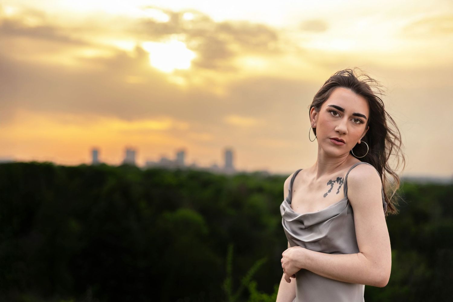 A woman poses with the sunset and the Fort Worth skyline.