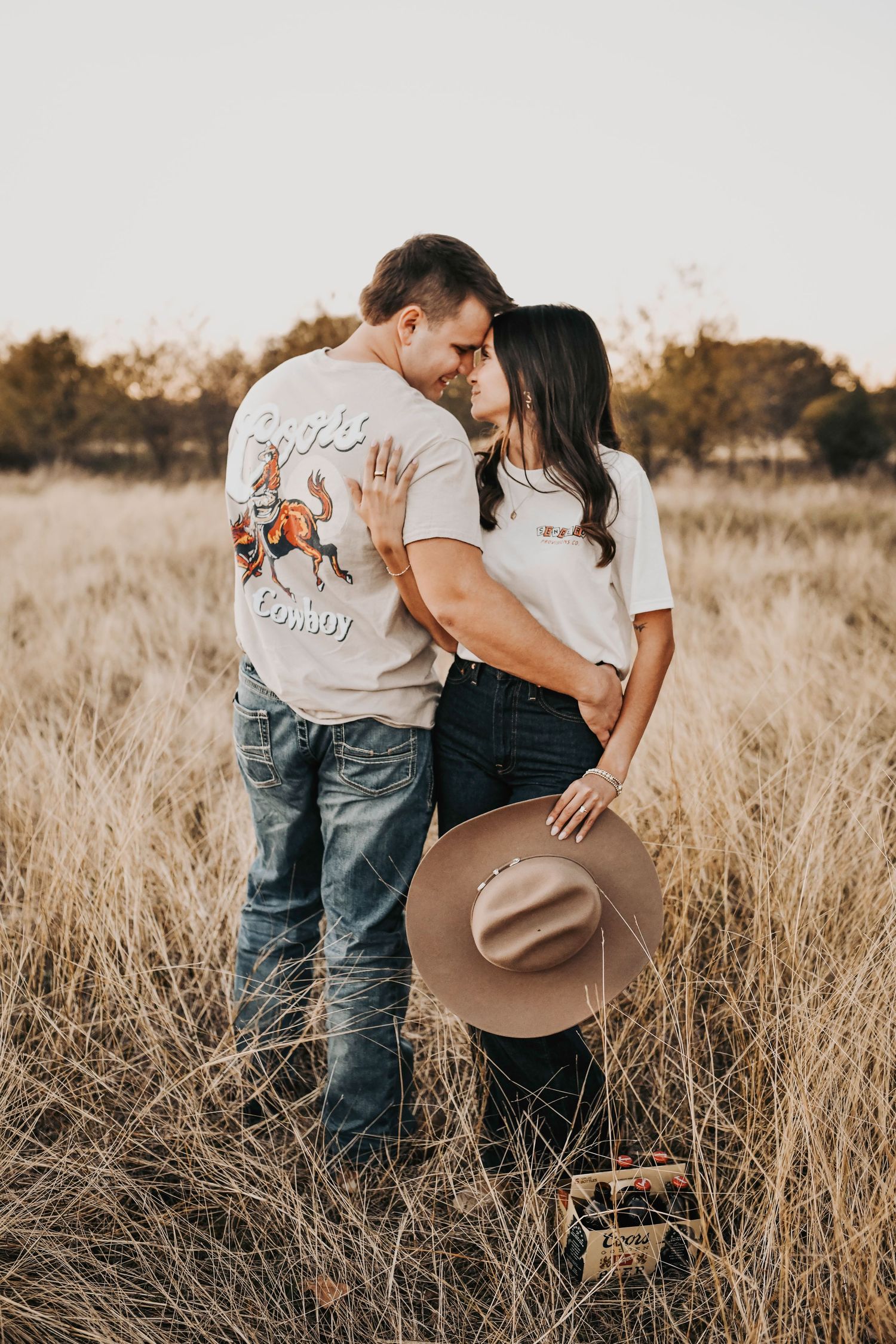 Rustic sunset engagement photos of a couple embracing in a golden field at sunset